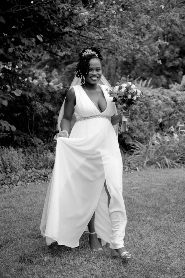 Bride walking across a lawn, black and white